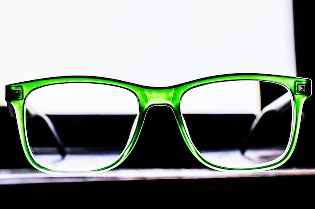 Glasses in front of the window Glasses for vision correction in a green frame