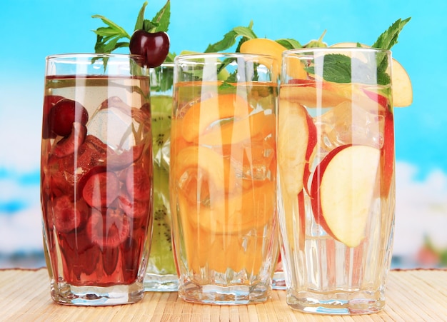 Photo glasses of fruit drinks with ice cubes on blue background