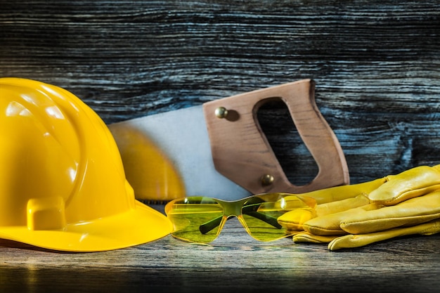 Glasses on gloves and handsaw with helmet