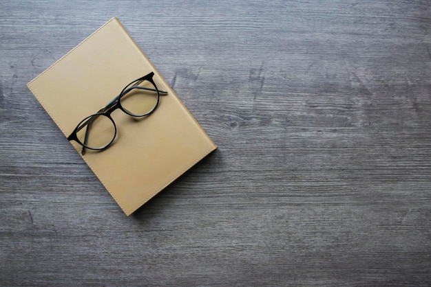 Glasses and gold notebook on wooden table Copy space