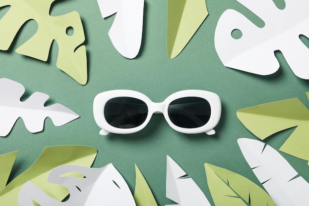 Glasses on a green background with paper tropical leaves