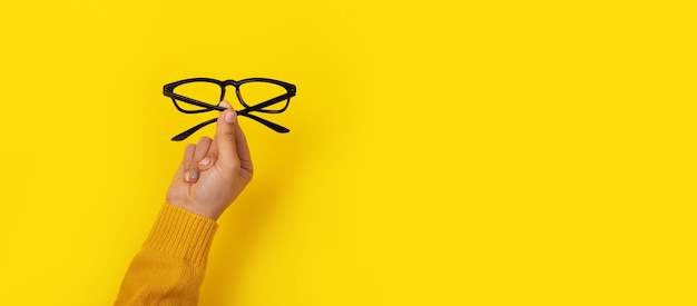 Glasses in hand on a yellow background, copy space template, banner.