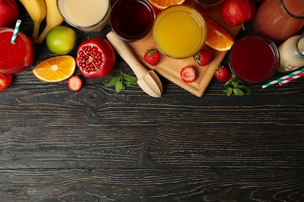 Glasses and jars with different juices on wooden