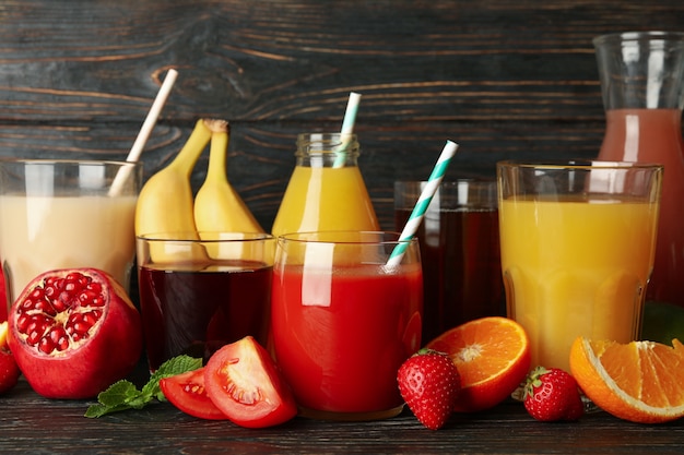 Glasses and jars with different juices on wooden