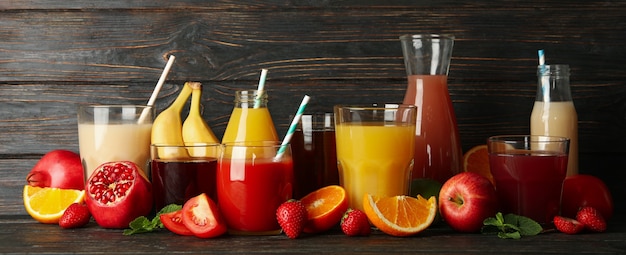 Glasses and jars with different juices on wooden 