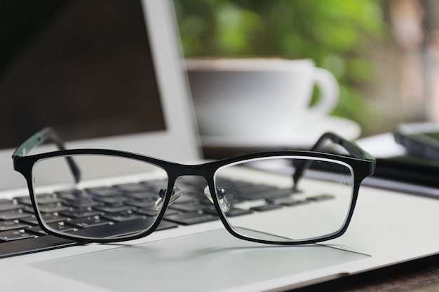 Glasses on the laptop with a blur of coffee in the background