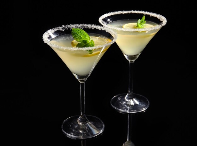 Glasses of lemon drop martini with slices of fruit on black background