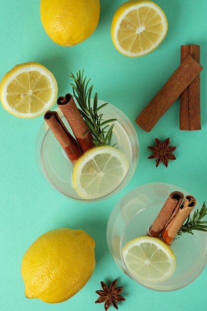 Glasses of lemonade with cinnamon and rosemary on mint surface