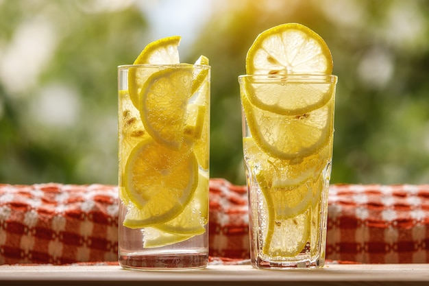 Glasses of lemonade with lemon on the sunny garden