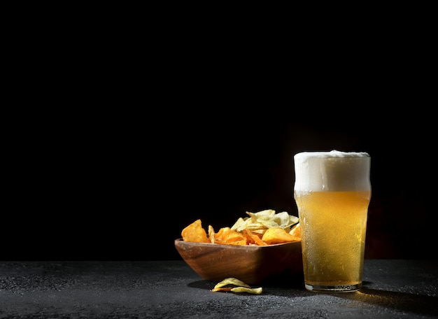 Foto vetri di birra chiara con le patatine fritte su oscurità