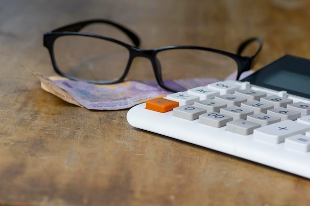 Glasses money and a calculator lying on wooden vintage
table