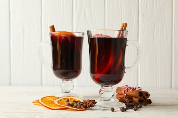 Glasses of mulled wine on white wooden background