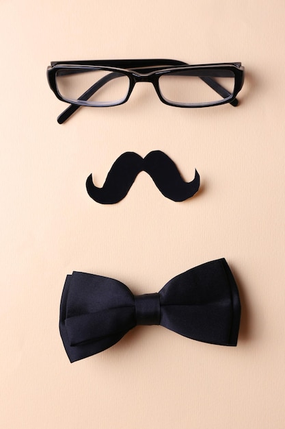 Glasses mustache and bow tie forming man face on beige background