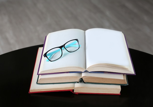 Photo glasses on open book on wooden table.