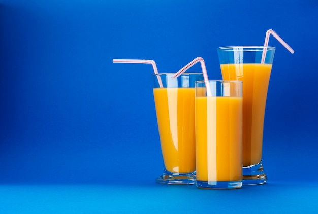 Glasses of orange juice on blue  with copy space