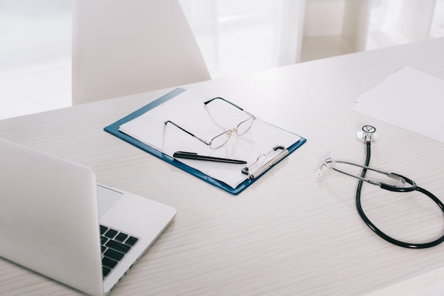 Glasses and pen on clipboard on working table in hospital