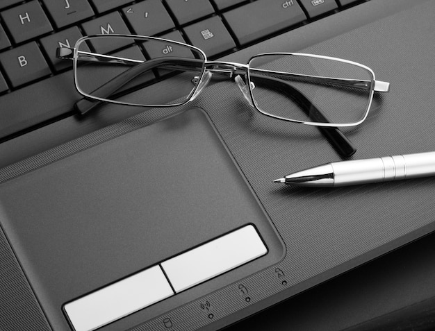 Glasses and pen on laptop