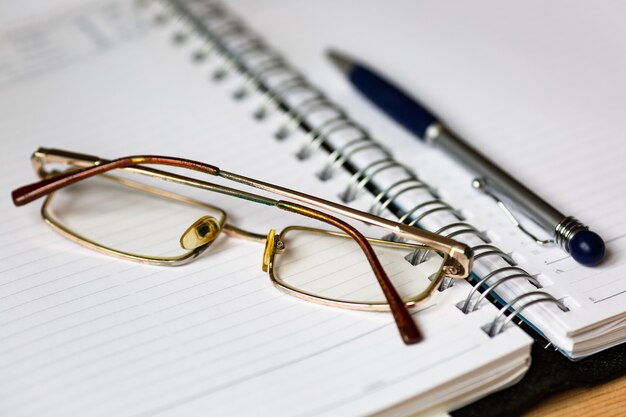 Glasses and a pen on an open notebook