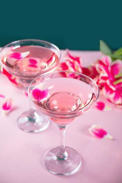 Glasses of pink cocktail with flowers and petals birthday party or valentines day romatic couple con...