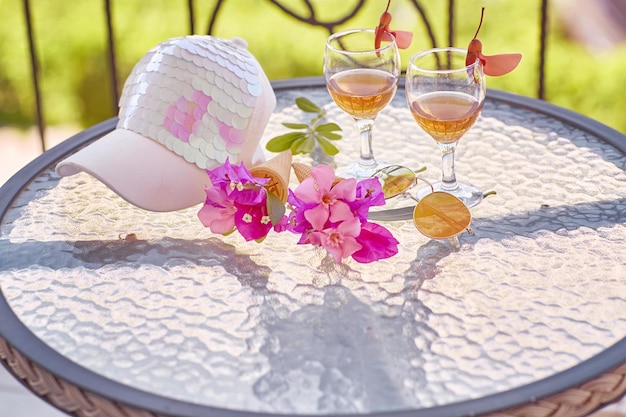 Glasses of pink wine pink flowers of bougainvillea and bright women cap Summer trendy creative