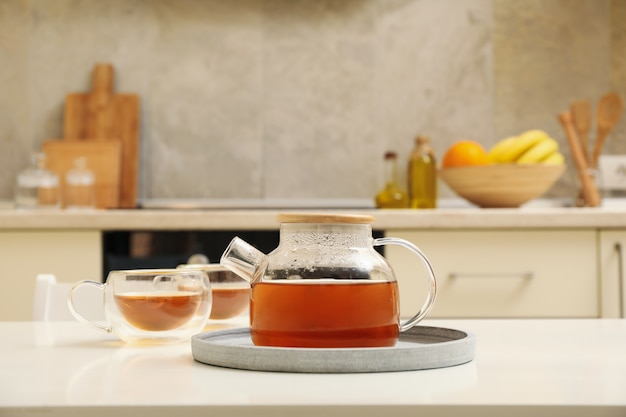 Photo glasses and pot of tea against kitchen interior