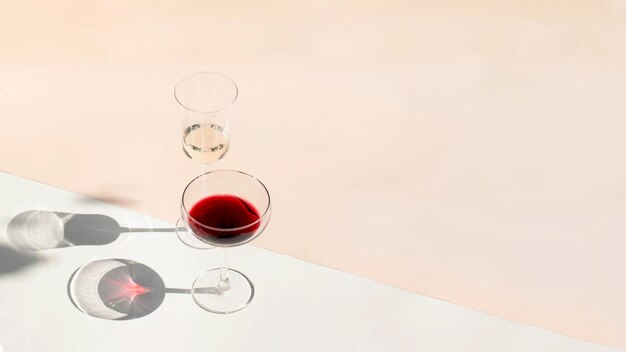 Glasses of red and white wine with hard shadows on the background