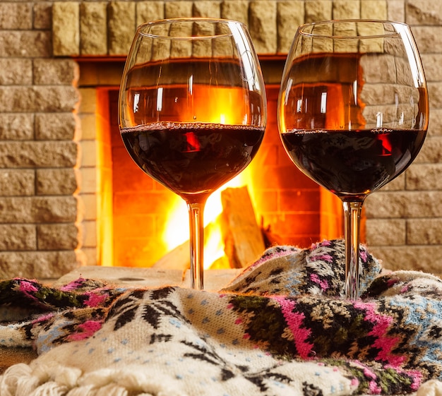 Glasses of  red wine before cozy fireplace.