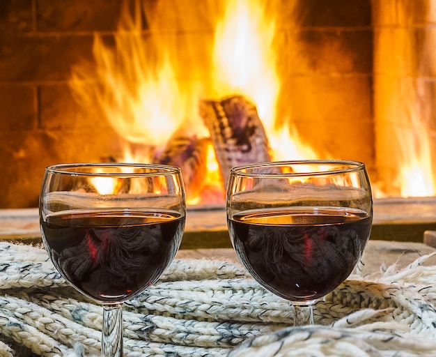 Glasses of  red wine before cozy fireplace.