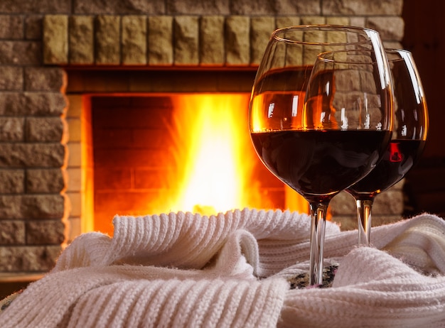 Glasses  of  red wine before cozy fireplace.