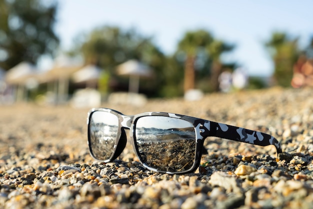 The glasses reflect the sun and the sea on the beach in summer.