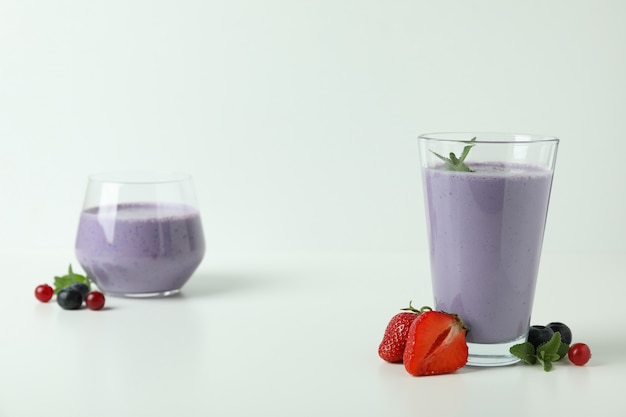 Glasses of smoothie and ingredients on white background