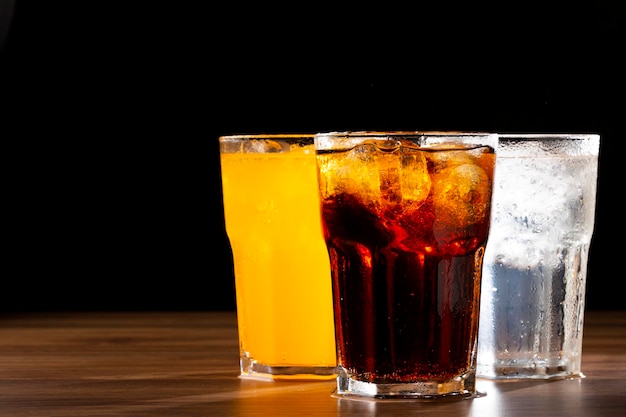 Glasses of soda flavors orange lemon and cola