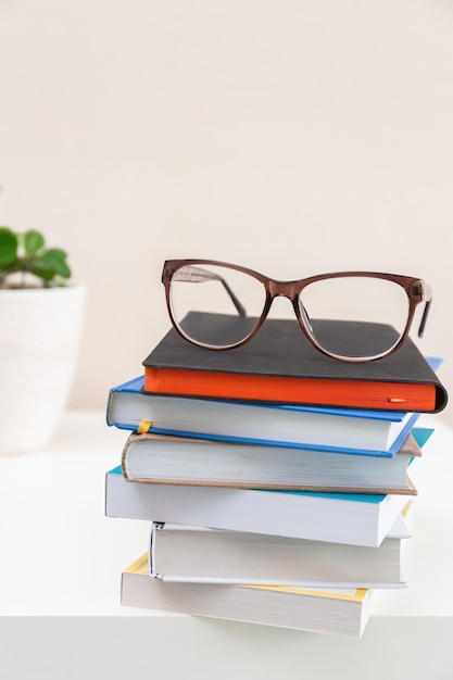 Glasses on a stack of books on light background Education learning and back to school concept