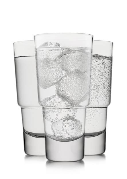 Glasses of still and sparkling water with ice and bubbles on white