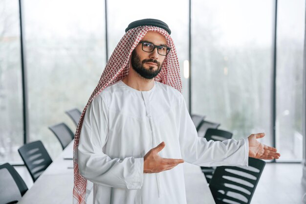 In glasses Successful Muslim businessman in traditional outfit in his office