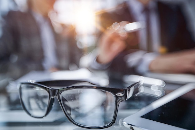 Glasses on the table in the office on a blurred background of colleagues