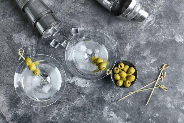 Glasses of tasty martini with olives on grunge surface