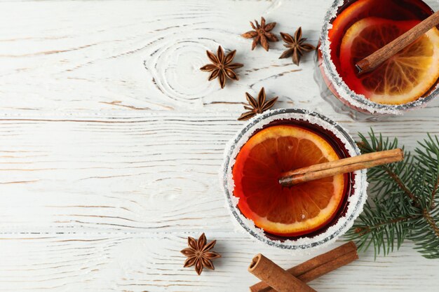 Glasses of tasty mulled wine on white wooden table, top view