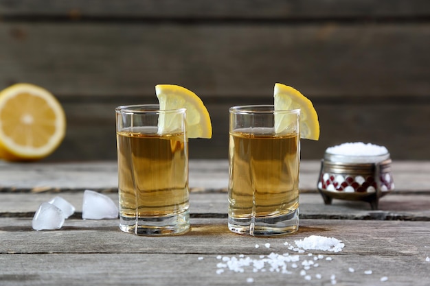 Glasses of tequila with lemon and salt on a wooden table