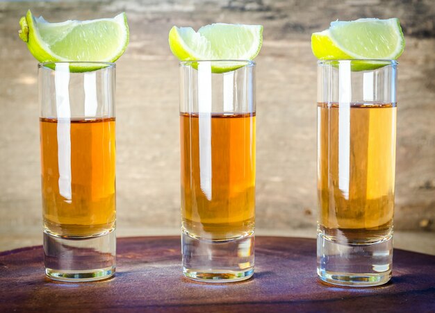 Photo glasses of tequila on wooden board