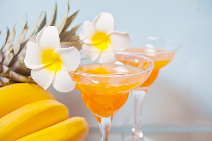 Photo プルメリアフランジパニの花と熱帯のエキゾチックなマルチフルーツジュースカクテルドリンクのグラス。 troicalビーチピクニックコンセプト。