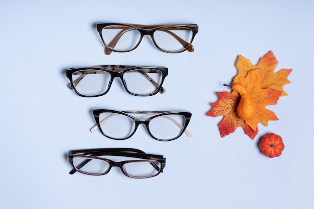 Glasses for vision on a blue background next to autumn leaves and pumpkin optical store vision test stylish glasses concept