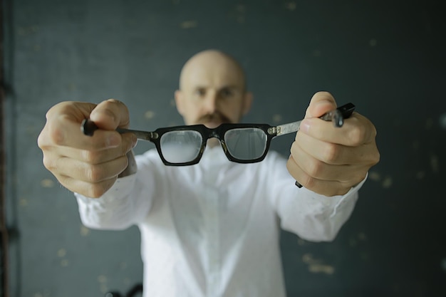 Photo glasses vision concept, man holds glasses in his hand.