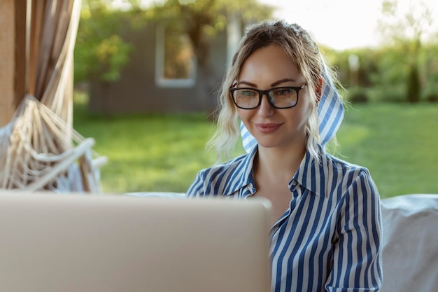 Occhiali per la vista elegante ragazza freelance lavora su un laptop fuori casa