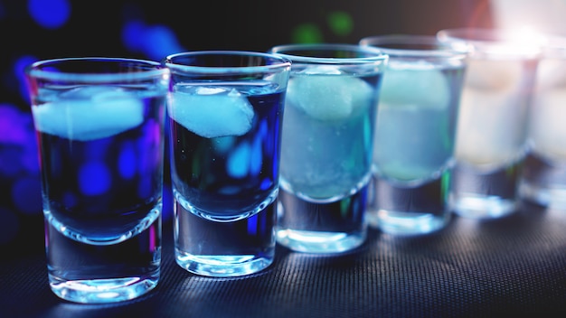 Glasses of vodka with ice. In bar - neon background