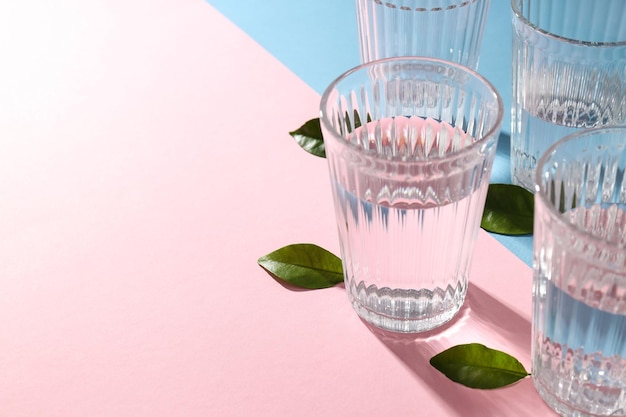 Glasses of water and leaves on two tone background