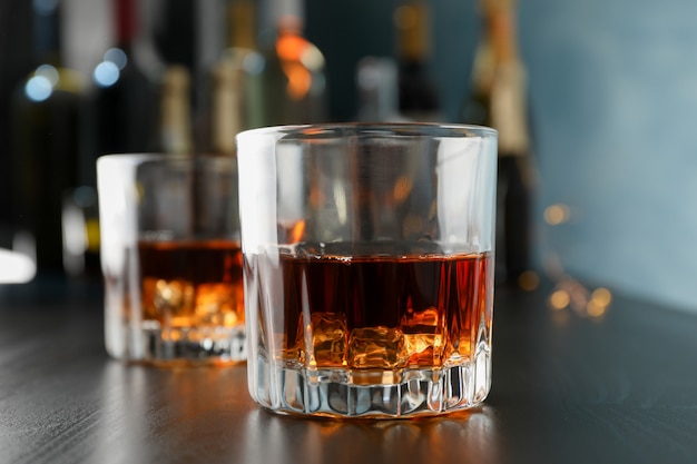 Glasses of whiskey on bar counter, close up