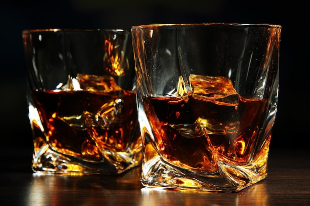 Glasses of whiskey on dark background