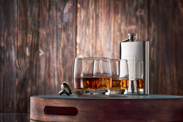 Glasses of whisky and a flask on the wooden table