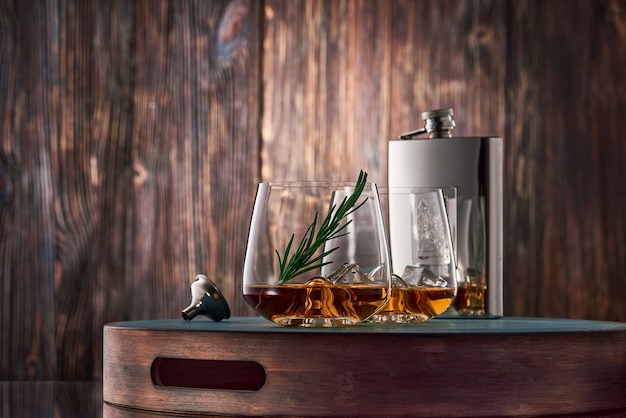 Glasses of whisky and a flask on the wooden table